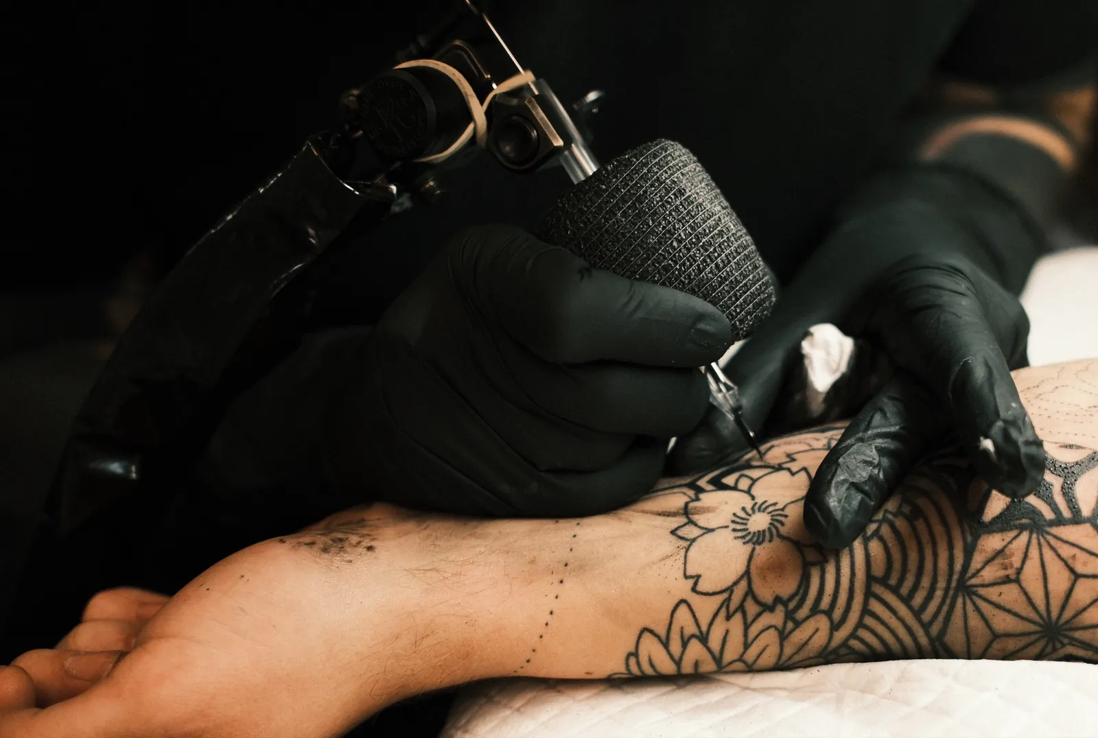 Close-up of a tattoo machine working a floral blackwork forearm at One Point Zero, Clifton, Bristol